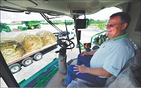 Bumpy road ahead: Chris Smith, co-owner of Smith Implements, sits in one of the company&rsquo;s popular John Deere S680 combines. The drought will likely affect the company&rsquo;s bottom line this fall. Staff photo by Tom Russo