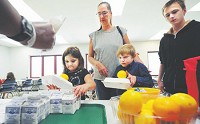 Maranda Prewitt, 8; Baily Jones, 7; and Michael Gilman, 14, along with caregiver Shelly Jones stand in line for meals at the Pat Elmore Center. Summer Meals for Kids is an offshoot of the Hancock County Hunger Summit. (Tom Russo / Daily Reporter)