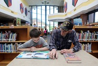 Eight-year-old Brett Pluta reads with his grandfather, Mike Kavanaugh, at the Hess Elementary School library recently. Teachers and students returning to Indiana schools this month are expected to meet a brand new set of standards. Staff photo by John J. Watkins