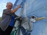 Darlene Vassil, a Hobart resident and Crown Point High School art teacher, paints a heron's wing in her newest mural on the restroom at Robinson Lake Park. Birds, she said, are a symbol of freedom. | Karen Caffarini~for Sun-Times Media