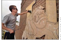 A fresh coat: 2003 Union High School graduate Chris Gentry sands the Dugger Bulldog mascot as he prepares it for a coat of paint on Friday at the new Dugger-Union school in Dugger. Below, the former Union High School is now the Dugger-Union school. The new school has entered a partnership with Indiana Cyber Charter School.&nbsp; Staff photo by Joseph C. Garza