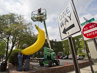 Randy Domeck, left, of Indianapolis Fabrications and Paul Szymchack of Sunbelt Rentals put a banana sculpture in place Monday at Varsity Apartments at Andrew Place and State Street in West Lafayette. The banana is used as a logo by Granite Management. (Photo: Michael Heinz/Journal &amp; Courier )