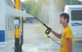 Raymond Wu sprays down a school bus as part of Greenfield-Central High School's first Day of Service in 2013. (File photo)