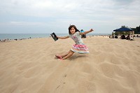 Claire Vinovich, 5, of Lakeville, Minn., plops down on a small sand dune recently while visiting the Indiana Dunes State Park with her family. The park attracts visitors from all over the country each year. Staff photo by John Luke