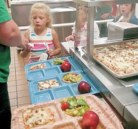 Breakfast pizza is a major favorite cafeteria option by students at Fremont Elementary School, as first grader Rileigh Poorman pays for her lunch. Her first-grade classmate, Libby Blizzard, right, waits her turn in line. Staff photo by Jennifer Decker