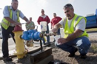 Jim Wehr, left, of the Jasper Water Department and Brett Kuebler of the city&rsquo;s electrical department, right, checked for water clarity before providing potable water to residents this morning at the intersection of Crossroads Avenue and State Road 164 on the city&rsquo;s east side. The hydrant pumps water from the Dubois Water Department, which is not affected by the boil order issued early this morning to residents who use Jasper water. Staff photo by Heather Rousseau