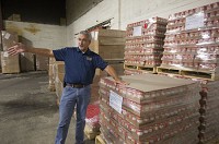 Dane Vida, president of IRBN in South Bend, stands inside his company warehouse, beside a shipment of canned food that will be sold to food banks in Indiana and several states. (SBT Photo/ROBERT FRANKLIN)