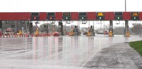 Motorists pass through the toll plaza at the Portage exit/entrance to the Indiana Toll Road on a rainy day in May. Indiana rebuffed calls from elected officials in the northern part of the state to reclaim the Toll Road after its private operator filed for bankruptcy. Staff photo by John Luke
