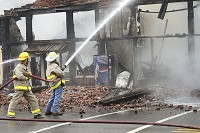 Local firefighters try to extinguish the flames on the remains of Laurie's Flowers, Rosie's Shirts and Gifts and other businesses located in the 200 block of JFK Avenue in Loogootee. Staff photo by Kelly Overton