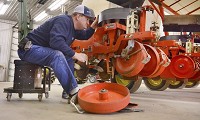 Farmer Kory Wilson, of Walton, co-owner of K Brothers Farm and Red Ripe Inc., does pre-planting season maintenance on his tomato setter machine. Staff photo by J. Kyle Keener