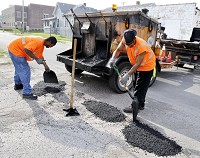 Filling potholes starts early, about 7 a.m., for city workers Eric Hamilton, left, and Raymond Johnson. Here, they're filling in a chuckhole on 21st Street between Meridian and Main streets.