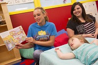 BEDFORD &mdash; Jacee Davis, left, reads to children including Raegan Clark, foreground, as fellow student Lauren Turner watches while at the North Lawrence Career Center child care center Friday. Neither are teen moms, but they are enrolled in the early childhood education class at the career center. The child care cente is for children of faculty and students. There are currently no children of students in the center. Staff photo by RIch Janzaruk II