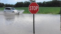 A car splashes through a flooded section of Indiana 2 Monday just north of Hebron. (Laura Schulte, Post-Tribune)