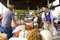 Scott Helt, left, with Sand Creek Farm in Jackson County, helps Cheyene, center, and John Schraft as they shop for produce with their son Kolten, two months, at the New Albany Farmers Market in this file photo.