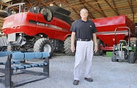 Ben Dillon, a farmer and inventor from the Logansport area, stands in his &ldquo;museum,&rdquo; the pole barn where earlier generations are stored of a machine he&rsquo;s developed combining the tasks of a combine harvester and a grain truck.