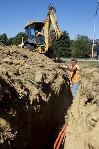 Brian Redman, front, and Carl Leonard, both of Mitchell, buried line last week for new high-speed Internet service being planned for Jasper by Smithville Communications. The crew was working on the corner of St. Charles Street and Pleasant View Drive. Staff photo by Ariana van den Akker