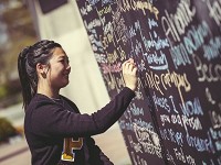 A student writes a message on a chalk wall as part of Purdue Day of Giving 2015. The day of giving was part of the silent phase of Purdue's $2 billion "Ever True" Campaign (Photo: Provided)