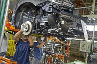 Production workers at the Subaru of Indiana Automotive plant, in Lafayette, perform front-end assembly on a Subaru Outback carried above them on a conveyor. The plant has almost 11 miles of conveyor line carrying vehicles and parts around the 3.5-million-square-foot production floor. Provided photo