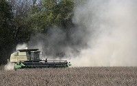 A combine speeds through a soybean field, kicking up a cloud of dust as it harvests the beans near Belmont in Brown County. Staff photo by David Snodgress