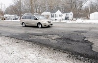 A minivan drives past patched pavement on 38th Street in Anderson on Friday. Tax increases on tobacco and gasoline are among five proposals for funding road maintenance. Staff photo by Don Knight