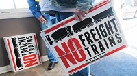 Visitors hand out "No Freight Trains" signs last week during a public meeting with the Surface Transportation Board in Valparaiso on the proposed freight rail line that would run through Porter County. (Kyle Telechan, Post-Tribune)