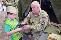 Brian P. Hart, a World War II re-enactor from Clarksville, Tennessee, explains to David Hawkins, 5, of Vincennes, the workings on a .45 caliber sidearm during the Indiana Military Museum's eighth annual 'Salute to Veterans of World War II' on Sept. 15, 2015. Staff file photo