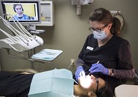 Right, Dr. Julie Kinsler, a dentist, checks dental office Manager Romelia Betancourt's teeth with the help of Erika, a Spanish-speaking interpreter, during a simulation of the new InDemand Interpreting system at Heart City Health Center's Simpson Avenue location on Wednesday, March 30. (Elkhart Truth photo/Amanda Wilkinson) 