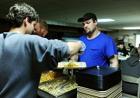 John Sartin, 32, passes through the dinner line as Derek Mellon, 28, places a serving on his tray in the basement of the Williams Emergency Shelter in Jeffersonville. Staff file photo