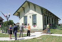 Waterloo Town Manager Tena Woenker, in blue at left, and Town Council President David Bolton, in orange shirt, chat with visiting guests Friday after a ribbon-cutting ceremony for the town&rsquo;s restored 1883 railroad depot. It will begin use as an Amtrak passenger station. Staff photo by Dave Kurtz