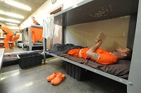 Inmate Nathan Reedy reads a book while in his bunk at the Hancock County Jail. Staff photo by Tom Russo