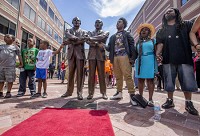 Spectators in downtown South Bend hold hands and sing, We Shall Overcome, after the unveiling of a sculpture Wednesday depicting the late Rev. Theodore Hesburgh holding hands with Dr. Martin Luther King Jr. Staff photo by Becky Malewitz