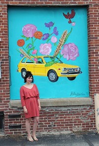 St. Paul resident Haley Burton poses next to the ural she painted for the back of the Decatur COunty Community Foundation building on Main Street. Staff photo by Amanda Browning