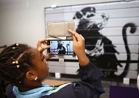 Zhana Leonard takes a photo of&nbsp;Haight Street Rat, created by the street artist Banksy. The piece was unveiled at the downtown Kokomo-Howard County Public Library on Friday, Aug. 4, 2017. Staff photo by Kelly Lafferty Gerber