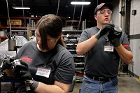 Caitlen LaMarche of Jasper, left, and Aaron Boehm of New Boston examined the pistons they were installing in an engine during training at Jasper Engines &amp; Transmissions on May 24. LaMarche and Boehm were two of seven college students involved in this year&rsquo;s Connect With Jasper internship program at JET. The interns started the program by learning how to build an engine or a transmission. Staff photo by Dave Weatherwax