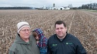 Farmer Mike Herlitz, on right, stands with his father, Wayne Herlitz, and his son, Harvey, 3, on the spot on his family's farmland that would be divided by the proposed railroad freight line. (Kyle Telechan / Post-Tribune)