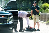 Jeffersonville Police Chief Kenny Kavanaugh, left, attends to a man he spotted laying on a sidewalk along 10th Street. JFD Sgt. Justin Ames calls in the incident to local EMS. Staff photo by John Hicks