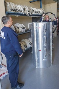 Firefighters Greg Ulery, left, and Jason Nolte see how the vacuum tube on the new grain rescue tube would be used to help rescue farmers trapped in a loaded grain bin. It was donated to the Logansport Fire Department on Wednesday by The Andersons. Staff photo by Fran Ruchalski