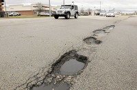 Motorists pass several potholes at the intersection of Scatterfield and Charles Street in Anderson on Friday, Feb. 23, 2018. Staff photo by Don Knight
