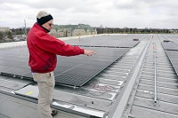  SUN POWER: Glenn Gilbert, director of facilities at Goshen College, examines the solar panels being installed on the roof of the Rec-Fitness Center on campus. Gilbert said there will be 924 panels installed. Staff photo by  Ben Miksell