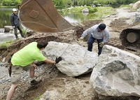 Japanese garden designer Sadafumi Uchiyama, above left, looks on as riggers connect a boulder to an excavator at Wellfield Botantical Gardens in Elkhart. Photo provided