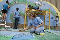 In this photo from 2009, Arielle Moir helps paint an Art Across the Americas mural to be installed along the B-Line Trail in downtown Bloomington. Staff photo by Jeremy Hogan