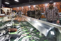 Tim and Becky Smith browse the selection of handguns Wednesday at Midwest Gun Exchange in Mishawaka. Tribune Photo/BECKY MALEWITZ