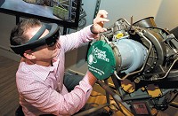 VisionThree Partner Jeff Hopler demonstrates how augmented reality could help a mechanic fixing an engine. (IBJ photo/Lesley Weidenbener)