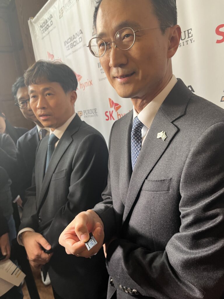 SK hynix CEO Kwak Noh-Jung, left, and Executive Vice President Woojin Choi hold a chip package that will be manufactured in West Lafayette. (Whitney Downard/Indiana Capital Chronicle)